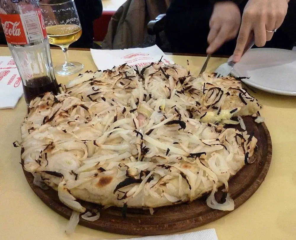 Porción de fugazzeta con mucho queso y cebolla