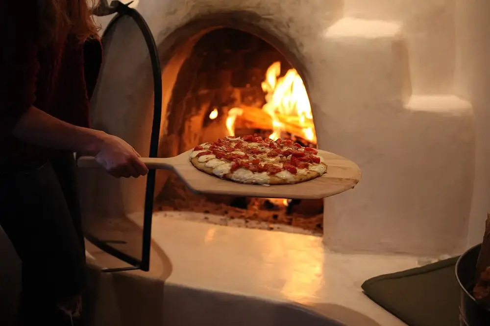 Pizza entrando al horno a leña en la pala